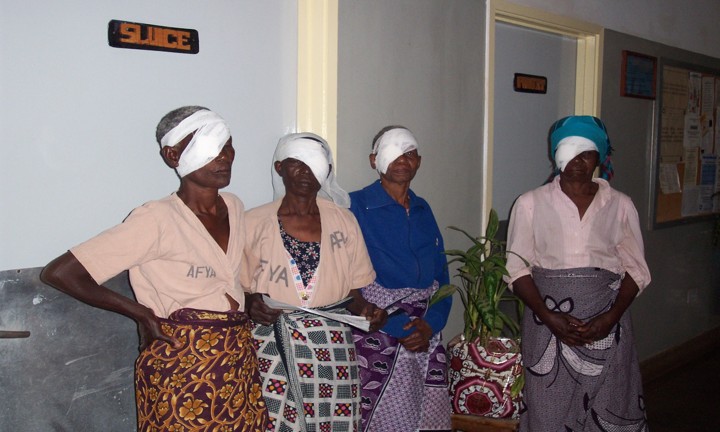 Four Tanzanian women wait post operatively, with bandages over one eye.